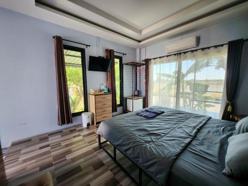 a bedroom with a bed and a large window at Maderlar Farm Restaurant & Resort in Ban Kao Lieo