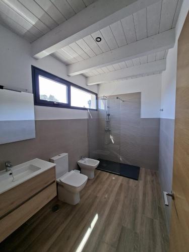 un bagno con un water, un lavandino e una finestra di Chalet Los Molinos a La Oliva