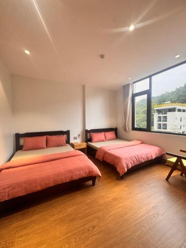 a bedroom with two beds and a large window at Cozy Hostel and Tours in Ha Giang