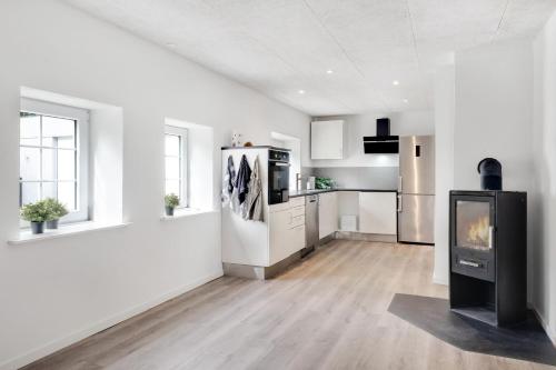 a white kitchen with a fireplace in the middle at Villa Surrounded By Nature in Vissenbjerg