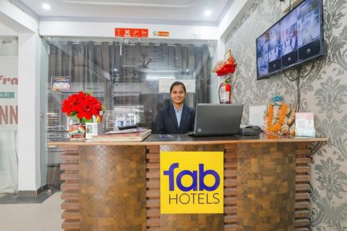 FabHotel Triveni في Jahāngīrābād: رجل يجلس في مكتب مع الكمبيوتر المحمول
