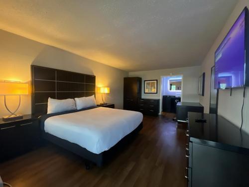 a hotel room with a bed and a flat screen tv at Boardwalk Suites Lafayette in Lafayette