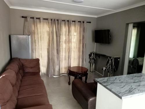 Ariah's Guesthouse and Self Catering في شرق لندن: غرفة معيشة بها أريكة وطاولة