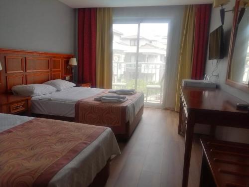 a hotel room with two beds and a window at Grand Nar Hotel ADULT ONLY - All Inclusive in Kemer