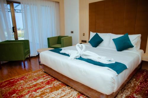 Buddha Regency Hotel في Gautam Buddha International Airport: غرفة نوم بسرير أبيض كبير مع وسائد زرقاء