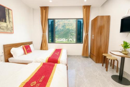 a hotel room with two beds and a table at Khách sạn Đức Phúc in Dồng Văn