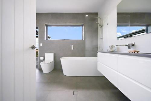 un bagno con vasca, WC e lavandino di Abode On North Ridge a Cooma