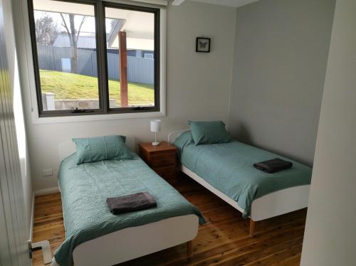 due letti in una piccola stanza con una finestra di Abode On North Ridge a Cooma