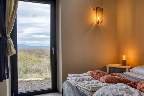 a bedroom with a bed and a window with a view at Tuscan Cozy Escape with View, Garden & Breakfast in CastellʼAzzara