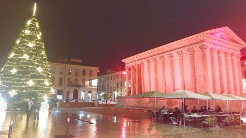 a christmas tree with people sitting at tables in front of a building at cocon des arènes et parking in Nîmes