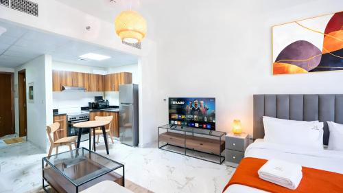 a room with a bed and a kitchen with a television at Marina Luxe Escape by Hala Holiday Homes in Ras al Khaimah
