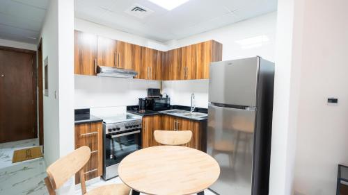 a kitchen with a table and a refrigerator at Marina Luxe Escape by Hala Holiday Homes in Ras al Khaimah
