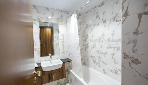a bathroom with a sink and a tub and a mirror at Marina Luxe Escape by Hala Holiday Homes in Ras al Khaimah
