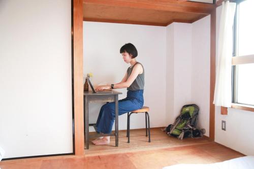 a man sitting at a desk in a room at Y Pub & Hostel Tottori in Tottori