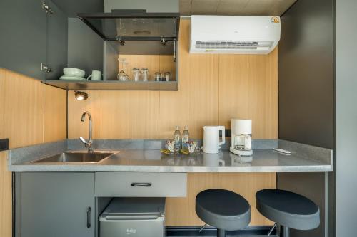 Cozy Nomad Cabin 1 Min Walk to Bang Tao Beach في Ban Lum Fuang: مطبخ صغير مع حوض و كرسيين