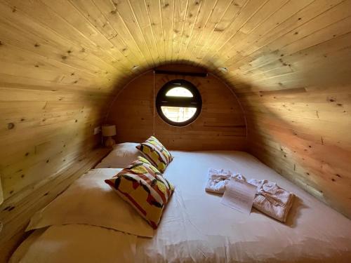 ein Bett in einem Holzzimmer mit Fenster in der Unterkunft Roulotte avec spa privé in Villé