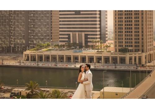 a bride and groom posing for a picture on a building at Keyrock - Zada Tower, Business Bay Lake-View Apartment in Dubai