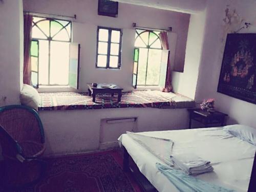 two beds in a room with two windows at Haveli Uma Megh Tourist Guest House in Būndi