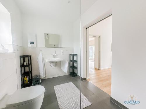 une salle de bains blanche avec toilettes et lavabo dans l'établissement Ferienhaus am Ringwall 19, à Duhnen