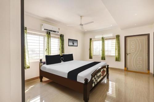a bedroom with a bed in a room with windows at Super Hotel O Ramaraopet Near Kakinada Beach in Kākināda
