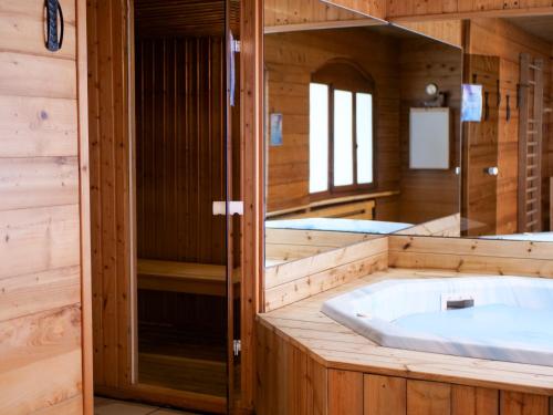 a large tub in a wooden bathroom with a mirror at Hôtel Les Airelles in La Clusaz