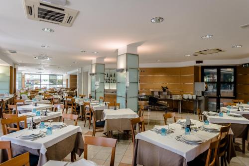 una sala da pranzo con tavoli e sedie bianchi di Hotel Taormina a San Benedetto del Tronto