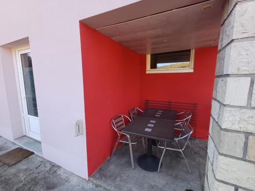 a table and chairs against a red wall at Chez Jade et Zoé in Ortholès