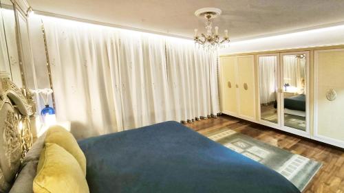 een woonkamer met een blauw bed en een kroonluchter bij Villagalicia360 in Bergondo