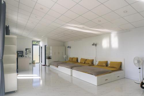 Cama grande en habitación blanca con almohadas amarillas en THỎ NON GARDEN CLOUDY OCEAN VIEW, en Blao Srê