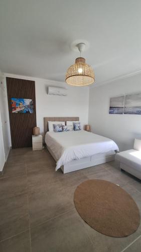 a white bedroom with a large bed and a chandelier at Bella Sunset Holidays - 3 min da Praia da Mareta in Sagres