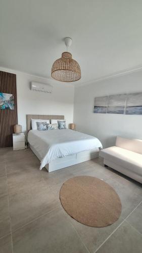 a white bedroom with a large bed and a couch at Bella Sunset Holidays - 3 min da Praia da Mareta in Sagres