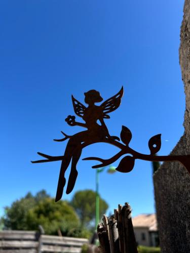 a statue of an angel sitting on a tree branch at Le Clos des Elfes in Saint-Martin-de-Londres