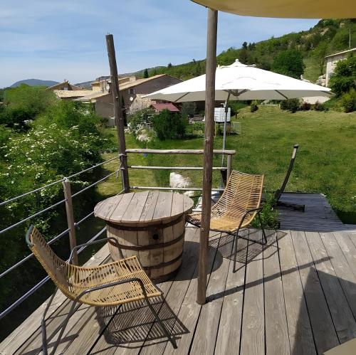 a table and two chairs and an umbrella on a deck at La Yourte Des Abeilles in Les Preyrauds