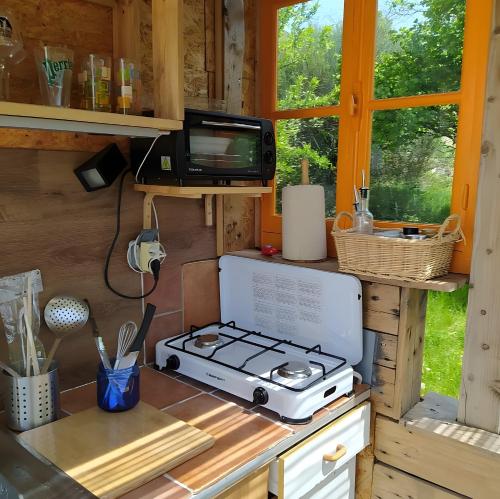 a kitchen with a stove and a tv on a counter at La Yourte Des Abeilles in Les Preyrauds
