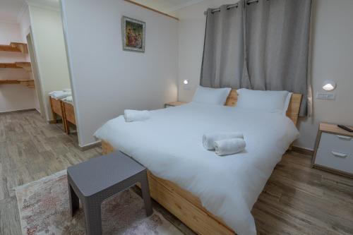 Un dormitorio con una cama blanca grande y una mesa en לה וילה - וילה משפחתית עם בריכה פרטית מחוממת ומקורה, en Bet Dagan