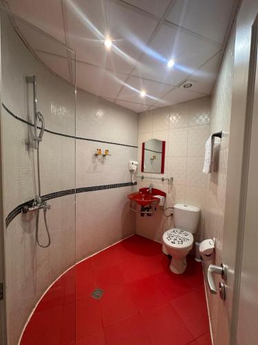 a bathroom with a toilet and a red floor at Cattleya Boutique Hotel in Ruse