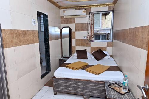 Un dormitorio pequeño con una cama y un espejo. en Hotel Ajanta, en Bombay