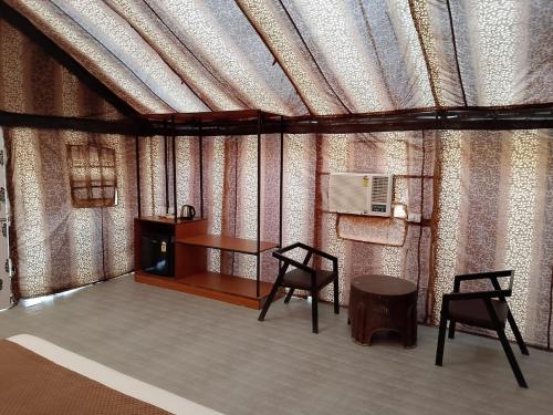 a room with two chairs and a table and a stove at Sandscapes Sam Jaisalmer by ADB Hospitality in Jaisalmer