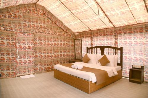 a bedroom with a bed in a room with wallpaper at Sandscapes Sam Jaisalmer by ADB Hospitality in Jaisalmer