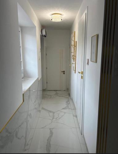 a hallway with white marble floors and a white door at Gold in Święta Katarzyna