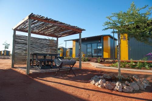 a pavilion with a table and a bench in front of a building at SleepOver Colesberg in Colesberg