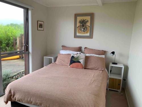 a bedroom with a bed with a large window at Ocean view haven in Matapouri
