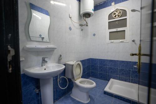 une salle de bain bleue et blanche avec des toilettes et un lavabo dans l'établissement GW Hostel, à Mascate