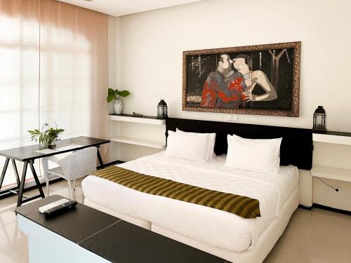 a bedroom with a large bed and a painting on the wall at Casa Artista By Kresna Hospitality in Seminyak