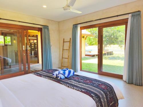 Un dormitorio con una cama y una ventana grande. en Villa Pesisi - 3 bdrs - beach walking distance, en Selong Belanak