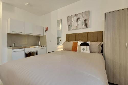 a bedroom with a large white bed and a kitchen at Aylward Queen Street, Studio Apartment Near City Centre, Gunwharf Quays in Portsmouth