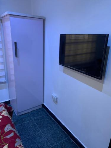 Una habitación con un televisor y una puerta blanca con un televisor. en Adel’s Place, en Abuja
