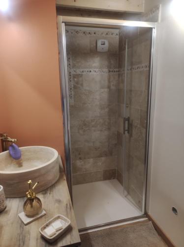a shower with a glass door next to a sink at Location en bordure du Trieux in Plourivo