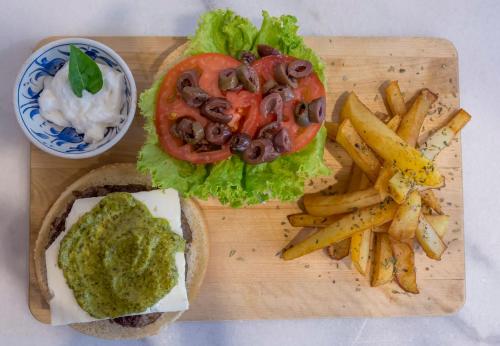 a wooden cutting board with a sandwich and french fries at Argonauta Hotel in Parikia
