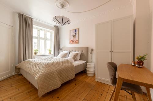 a bedroom with a bed and a desk and a window at Lovely City Apartments in Vibrant Area of Copenhagen in Copenhagen
